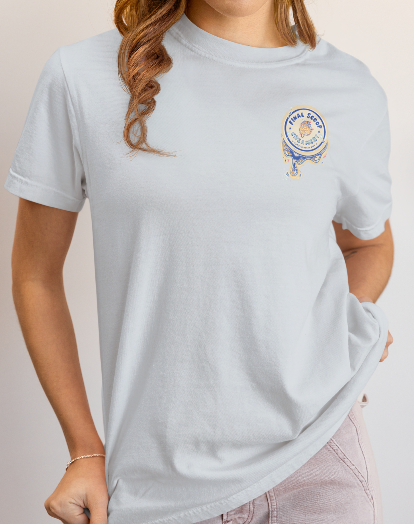 Person wearing a light blue t-shirt with a logo on a plain background