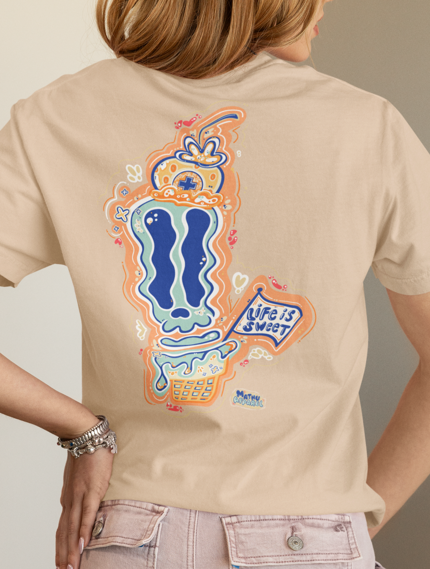 Person wearing a beige t-shirt with a colorful graphic on the back, standing against a neutral background.