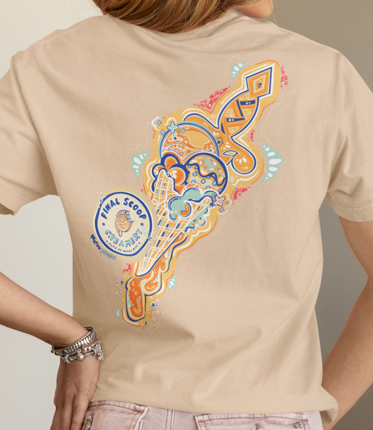 Person wearing a beige t-shirt with colorful graphic design on the back