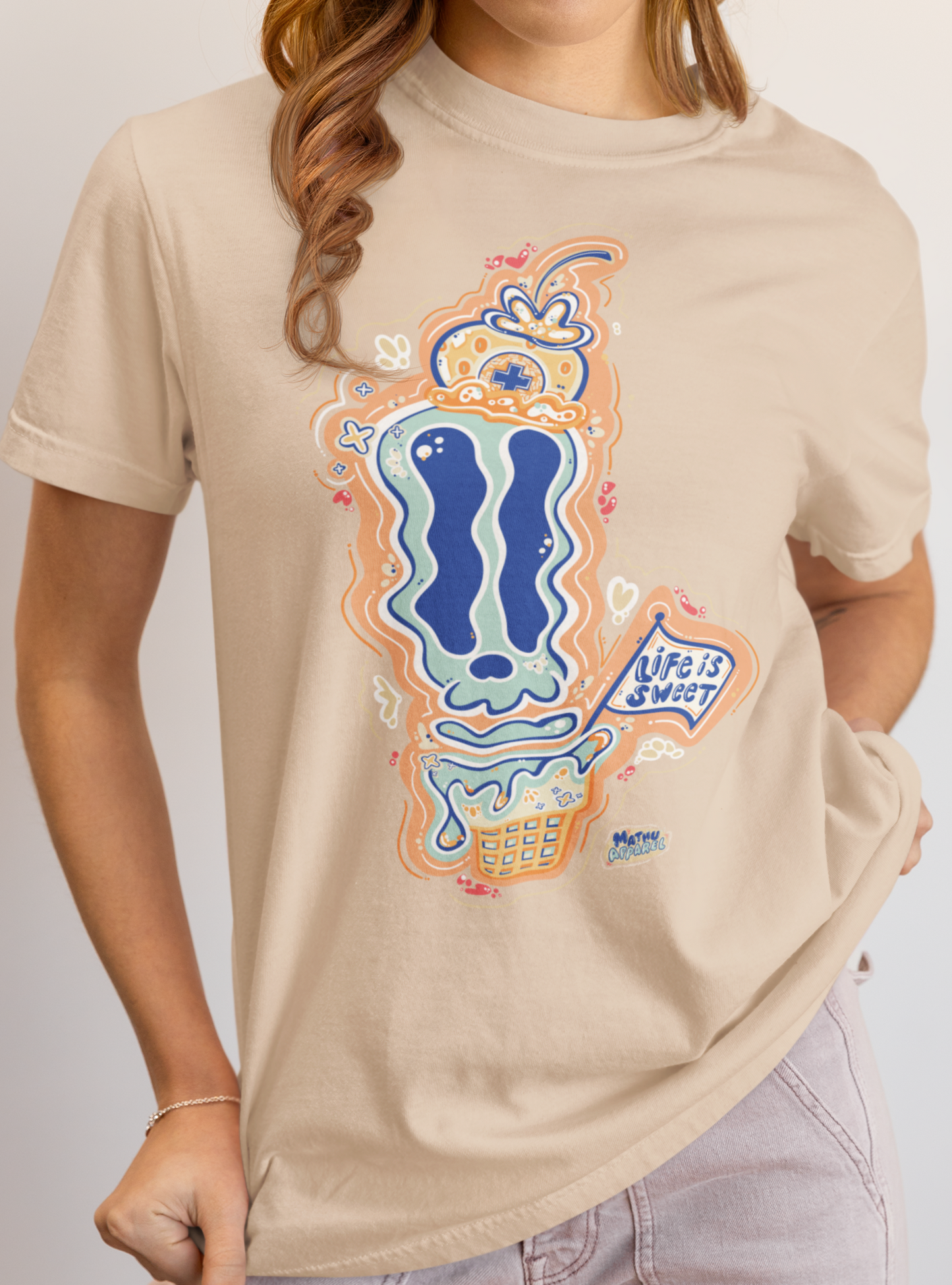 Person wearing a beige t-shirt with a colorful graphic design on a plain background