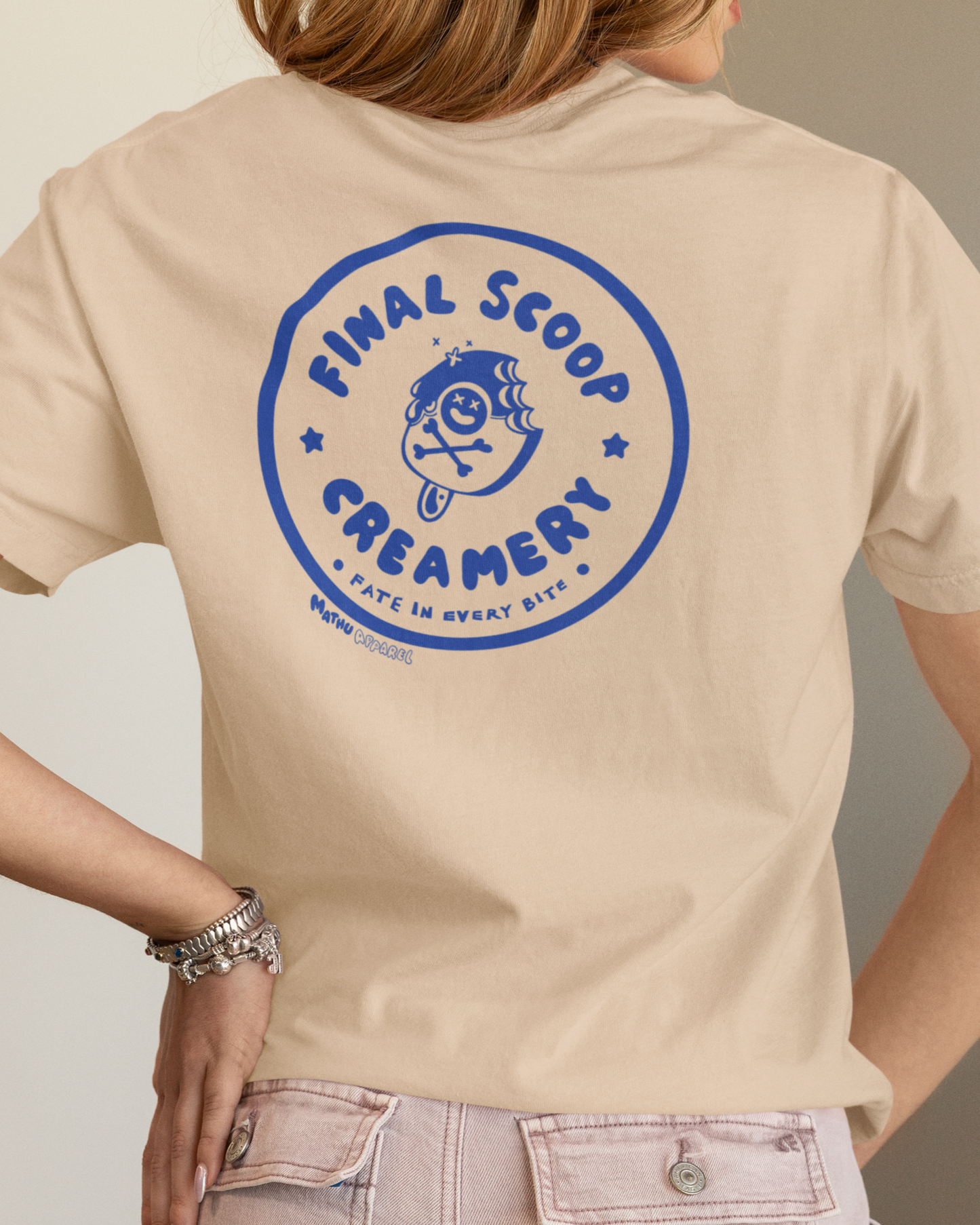 Person wearing a beige t-shirt with a blue logo and text on the back.