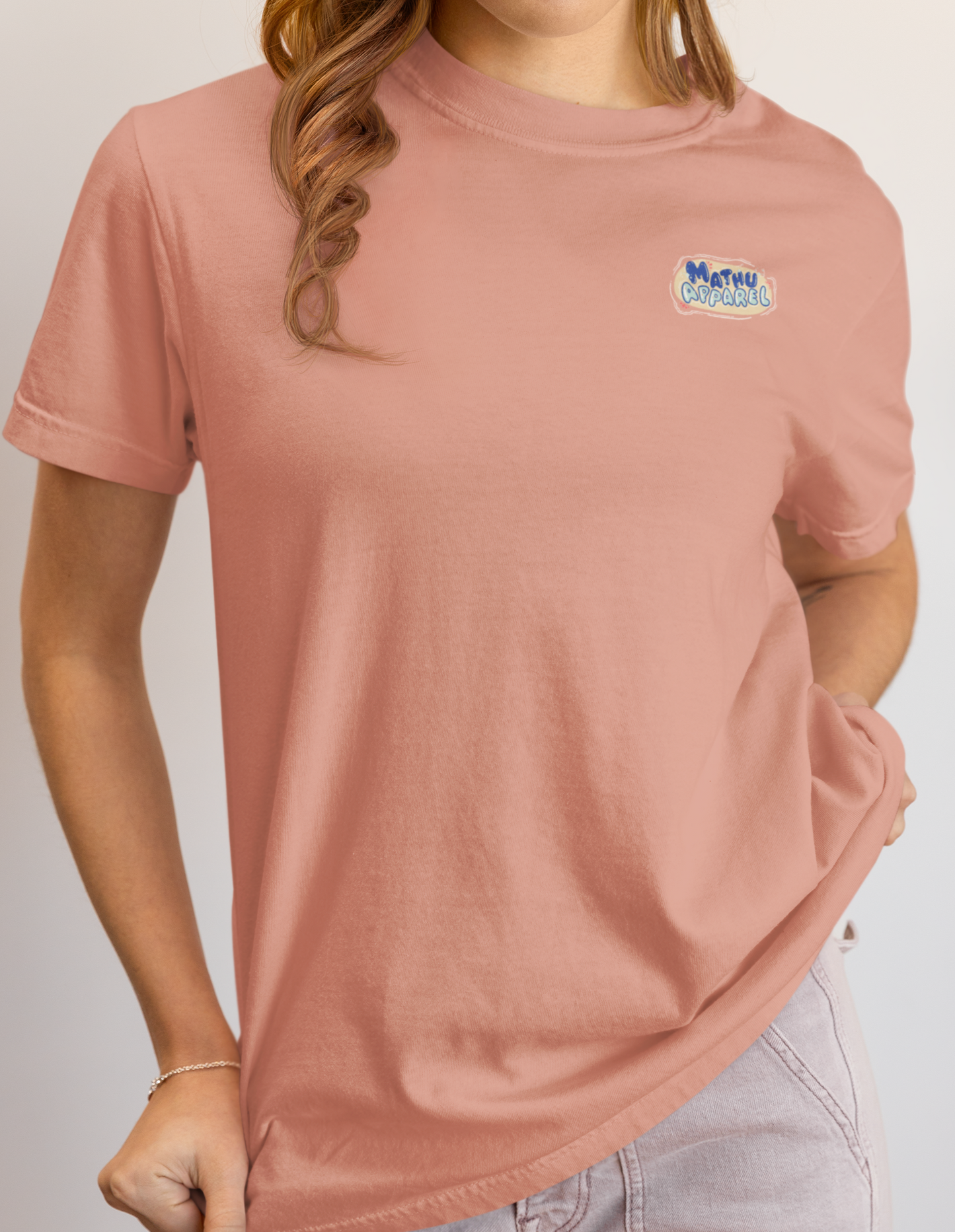 Person wearing a pink t-shirt with a logo on a plain background