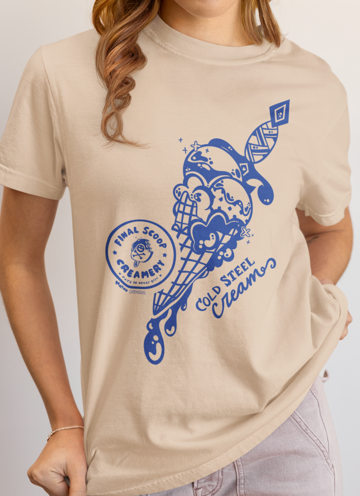 Person wearing a beige t-shirt with a blue graphic design on a plain background