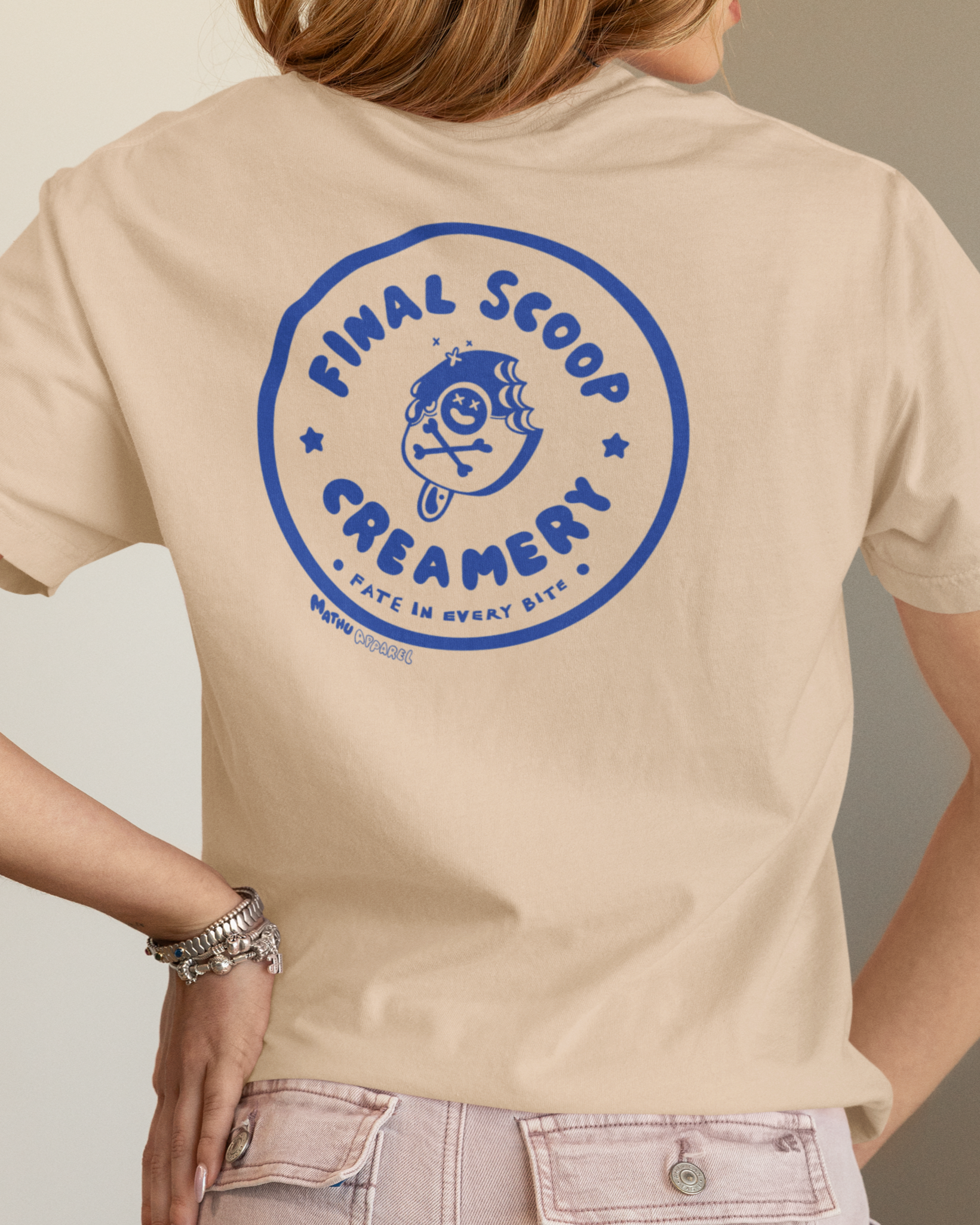 Person wearing a beige t-shirt with a blue logo and text on the back.
